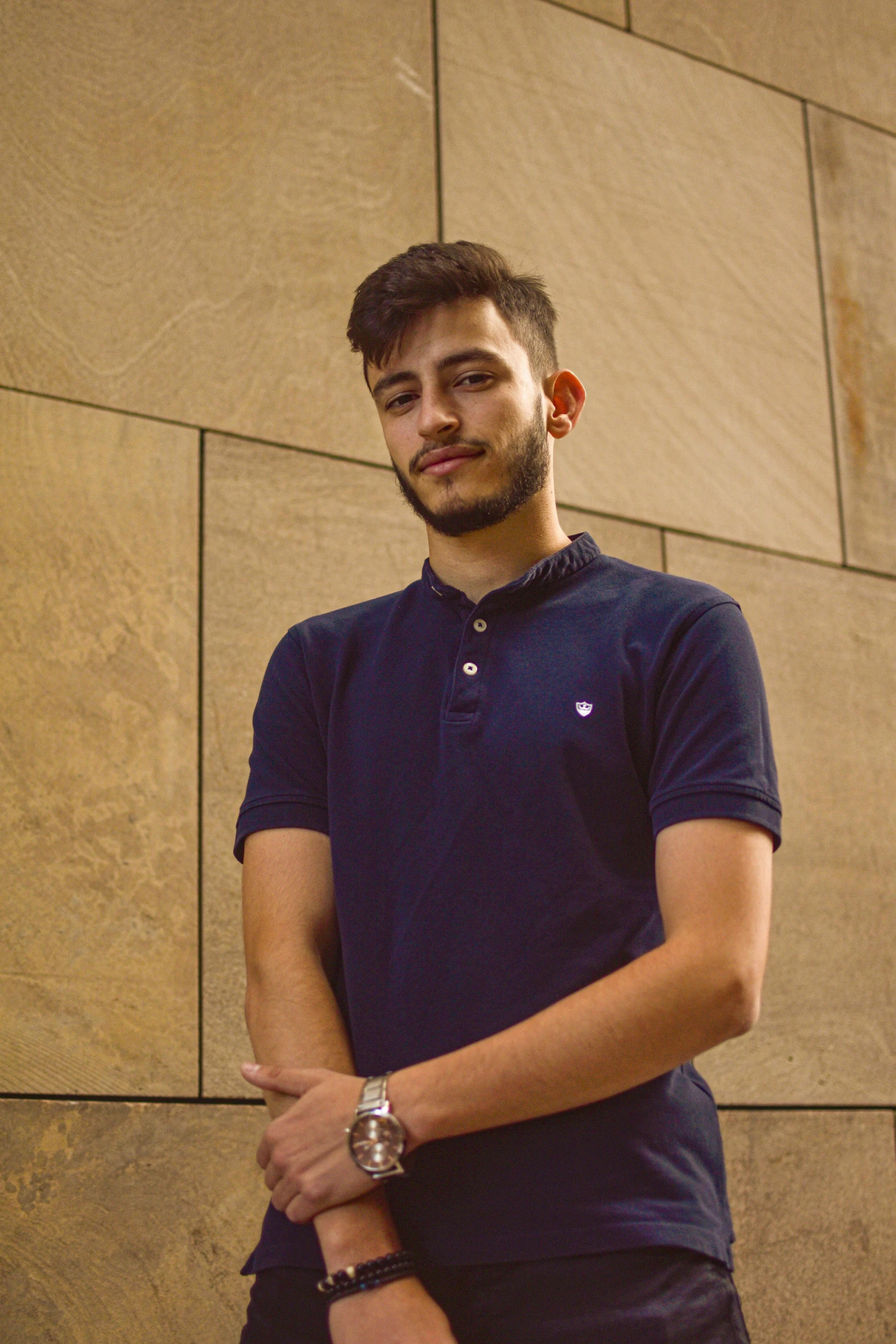 the man is standing in front of the wall, wearing blue