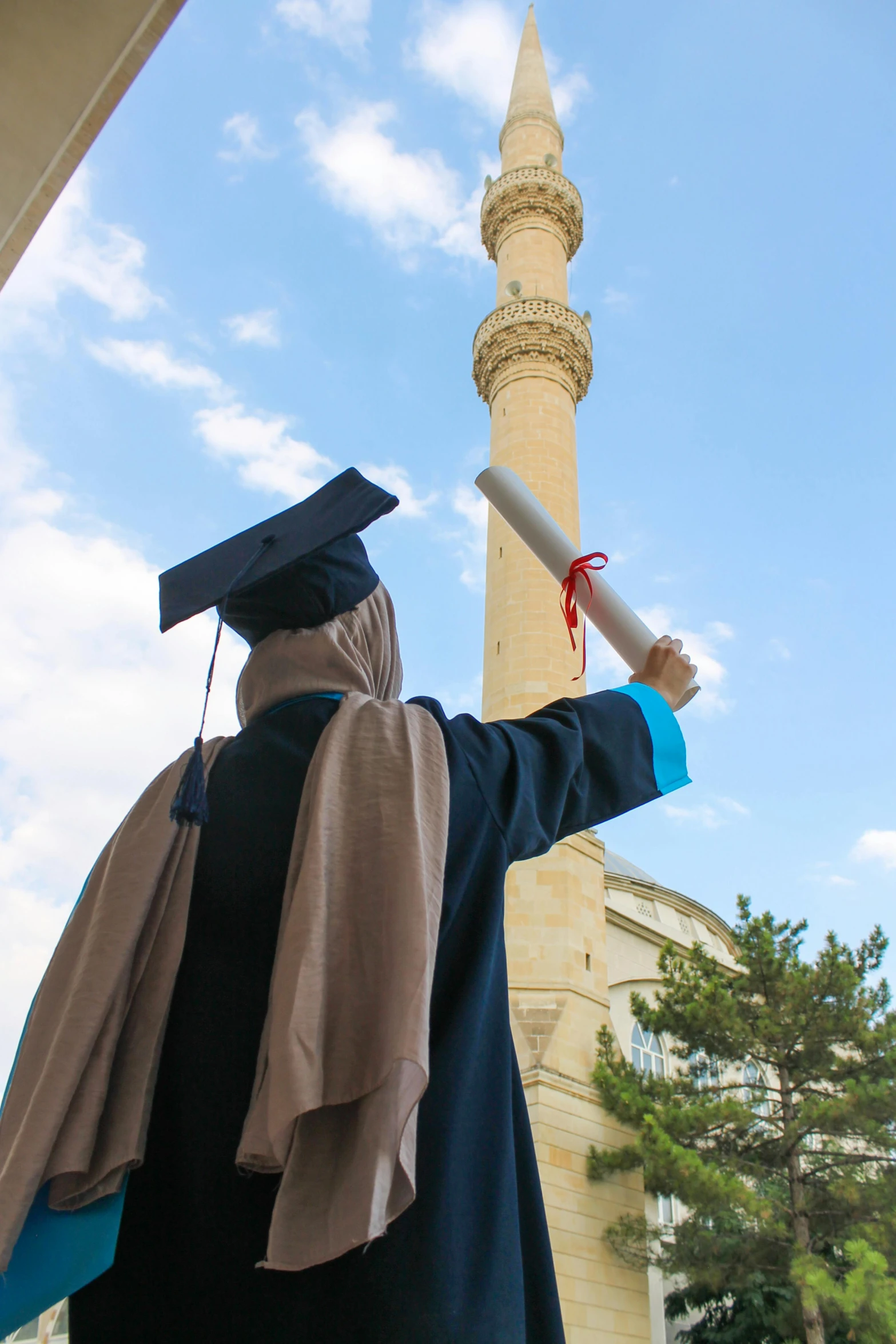 a man wearing a graduation gown standing in front of a tall tower