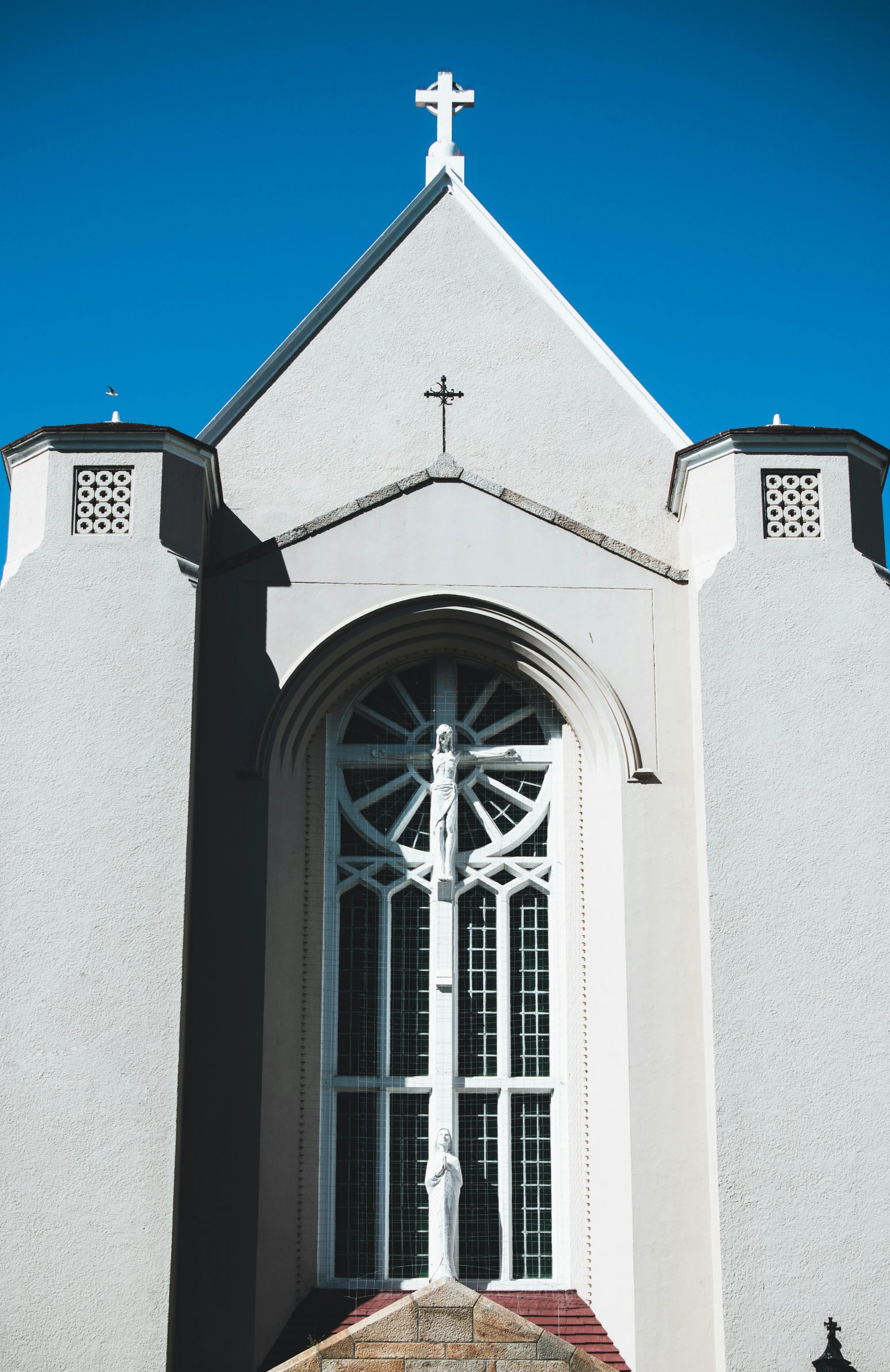 this church has an arched window and a cross on the wall