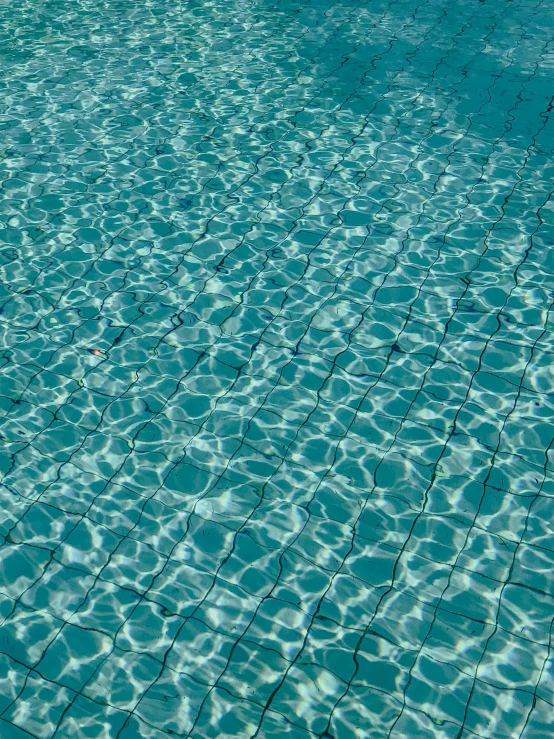 a swimming pool with clear blue water and lines in the ground