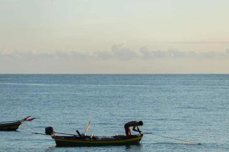 a man standing on the front end of a small boat