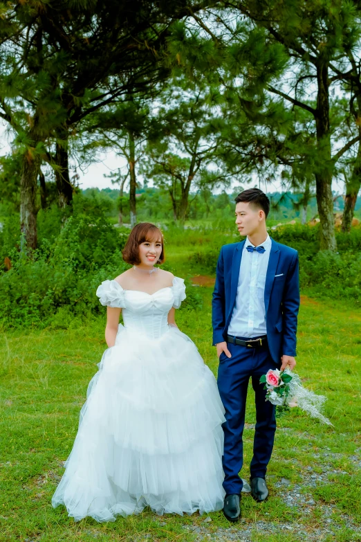 a young woman in white wedding dress next to a man in blue tuxedo