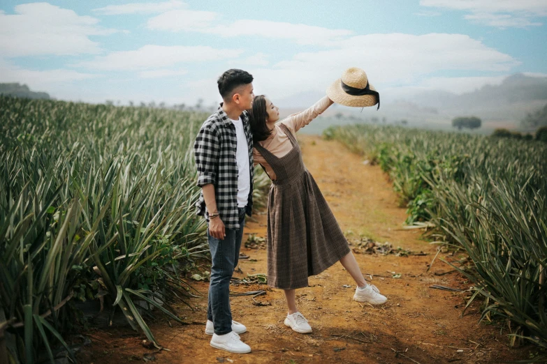 a man and woman are holding up hats in a field