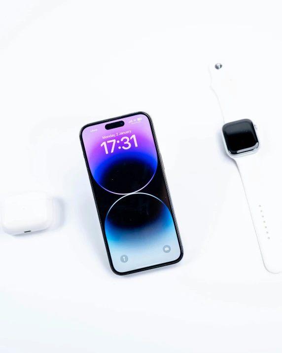 an iphone and apple watch sitting on top of a white table
