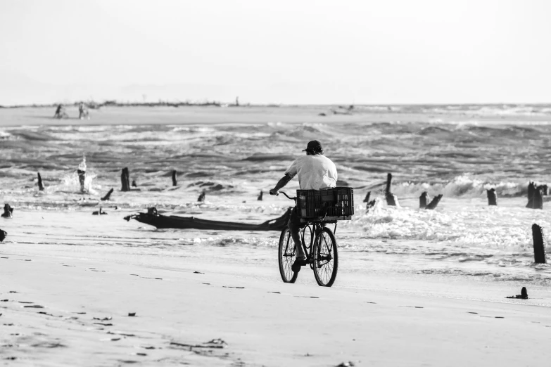 a man on a bike at the beach in front of a boat