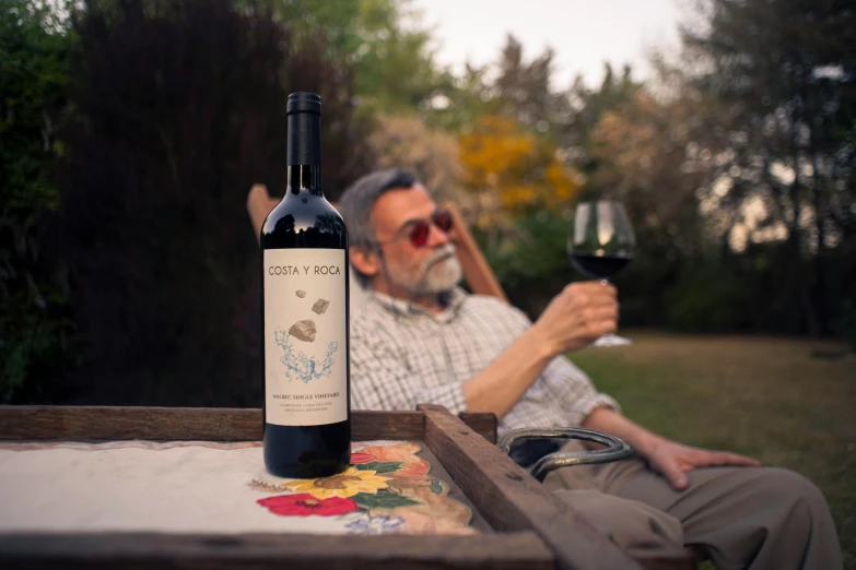 an old man drinking wine next to a glass