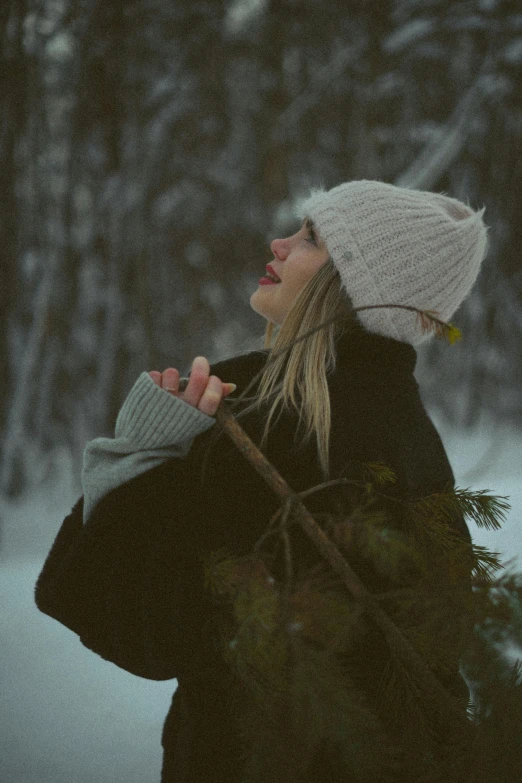 a young woman walking through the snow holding a tree