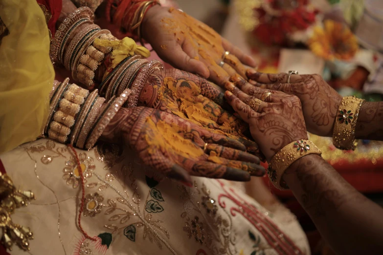 several indian brides holding hands together, both showing off their painted hands