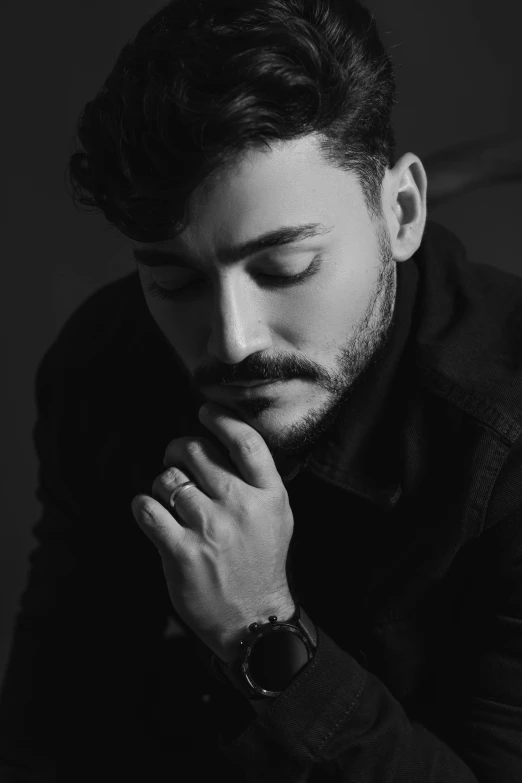 a man in a black shirt with his chin resting on his hand