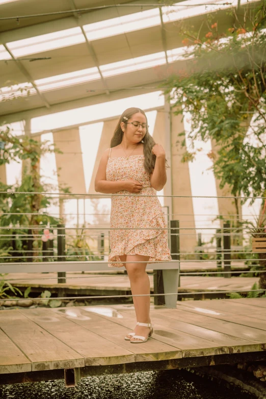 a woman wearing a pink dress and heels is standing on a bridge with her arms around her waist