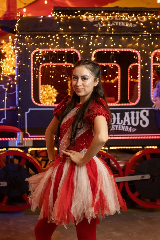 a woman is standing by a train and christmas lights