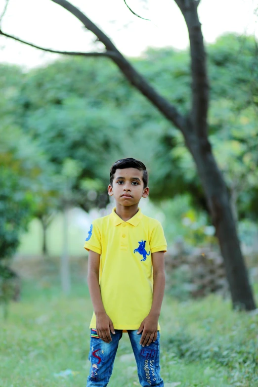 a  in a yellow shirt standing next to trees