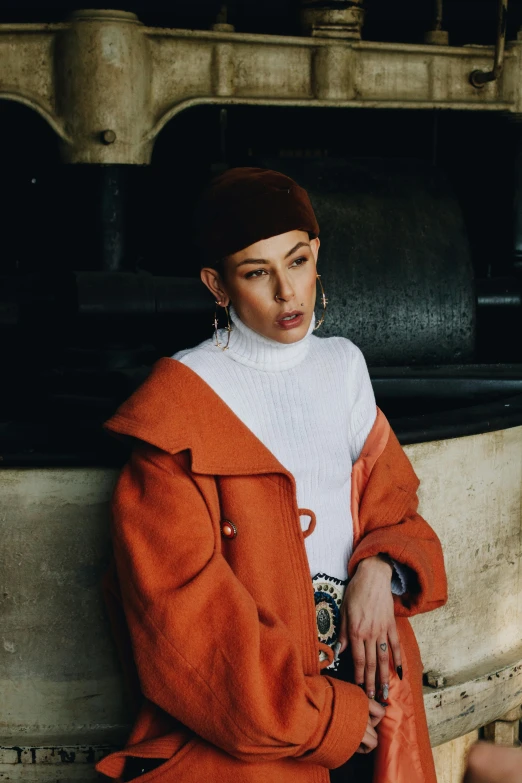 woman wearing a white shirt and orange coat with large gold hoop earrings