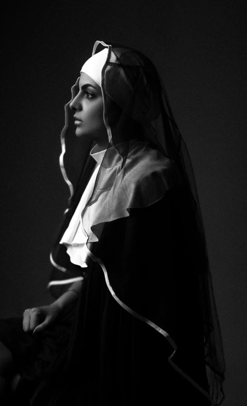 a nun holding a lit candle and looking away from the camera