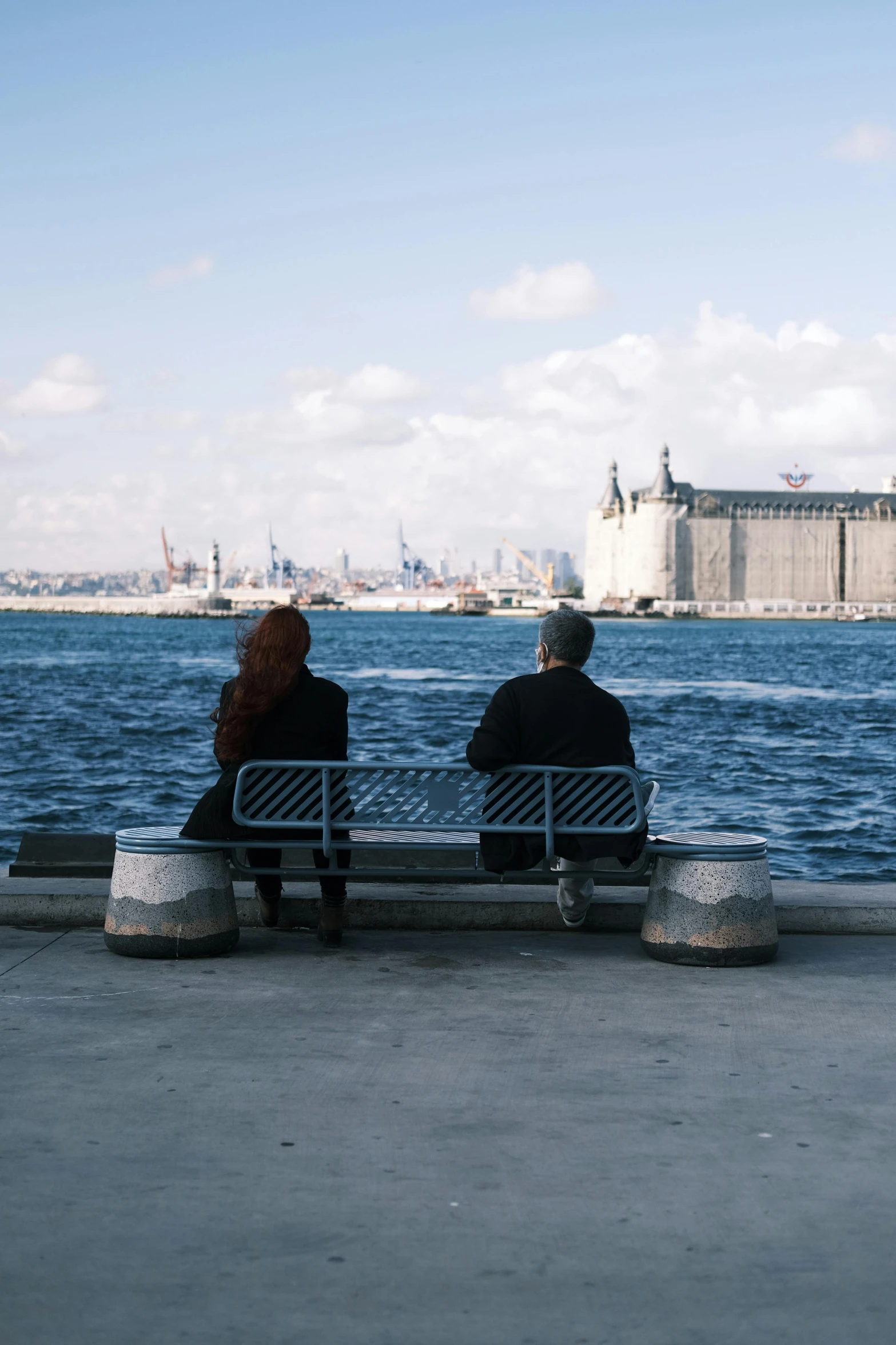 two people sitting on a bench near the ocean