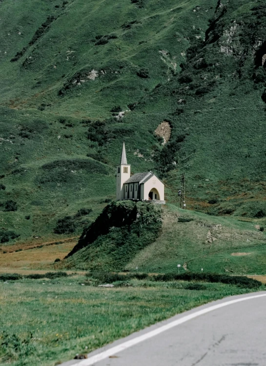 a road runs beside a hillside with a church on it