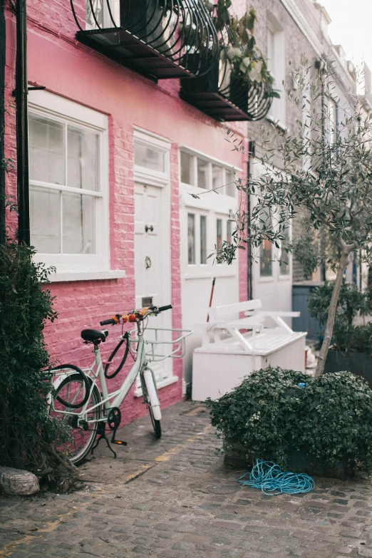 there is a bike parked next to a pink house