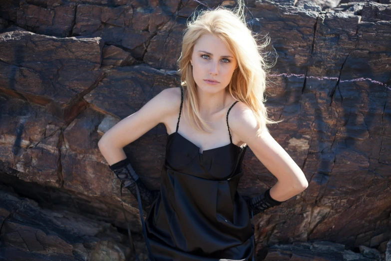 a woman posing in front of a rocky cliff