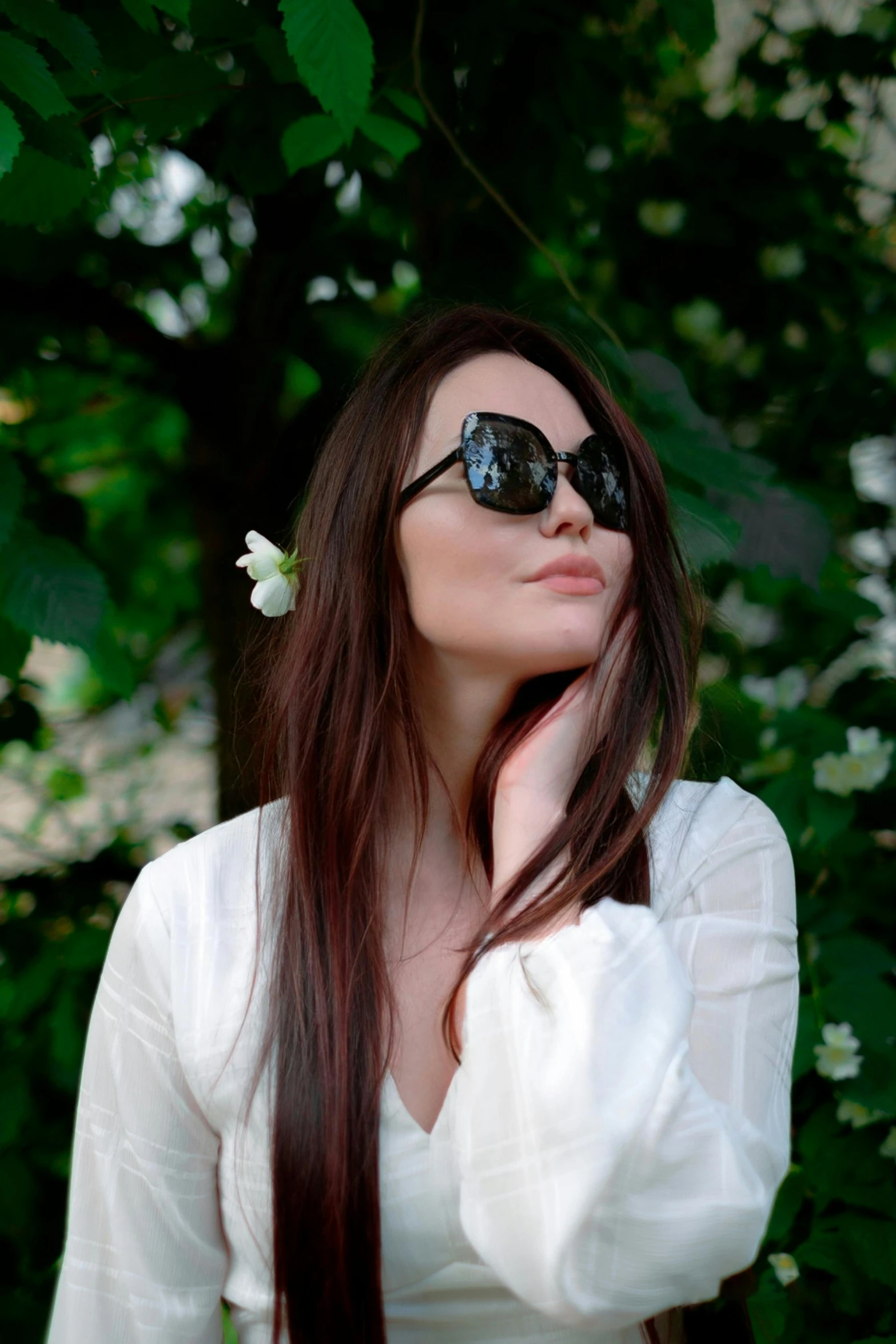 a woman in sunglasses is holding her hand to her face