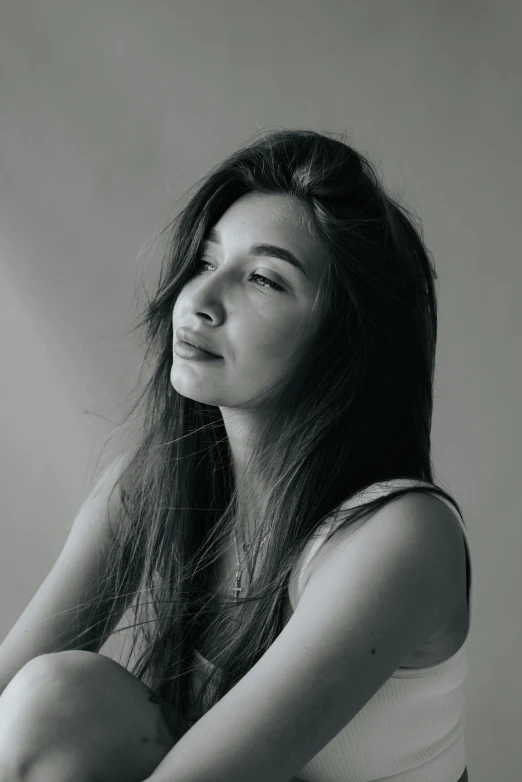 a young asian woman sitting cross legged and posing for the camera