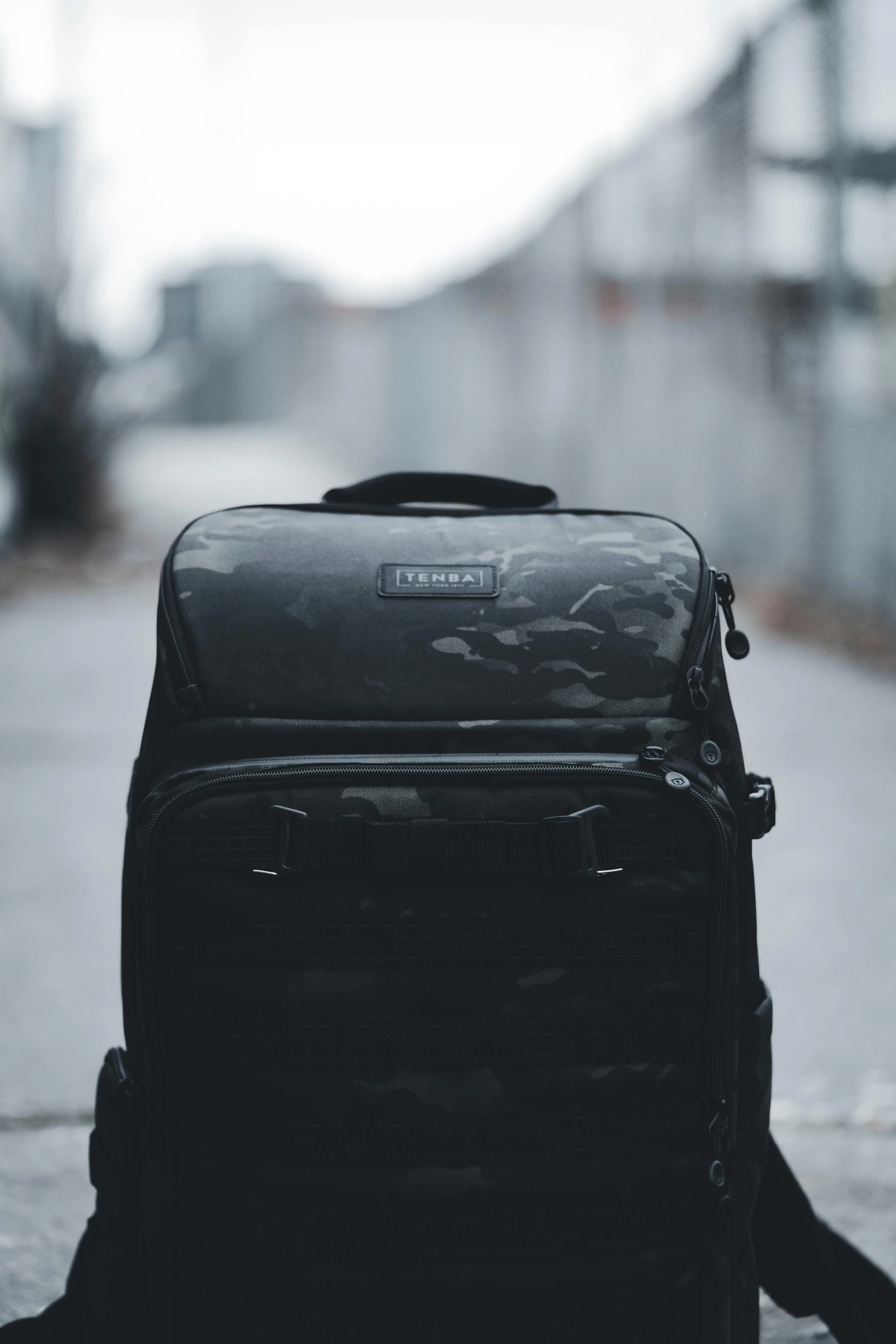 black backpack sitting on the sidewalk in the rain