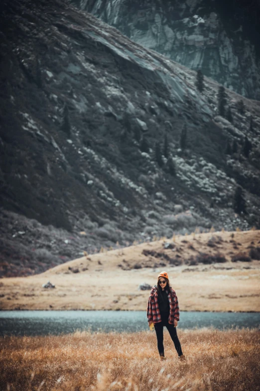 a woman standing in a field near a mountain
