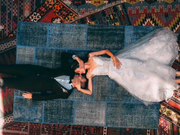 a newly married couple are laying on a rug in the sun
