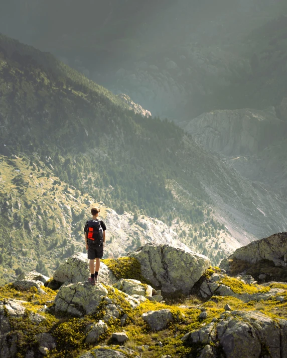 man standing on top of a rocky outcropping with a mountain in the background