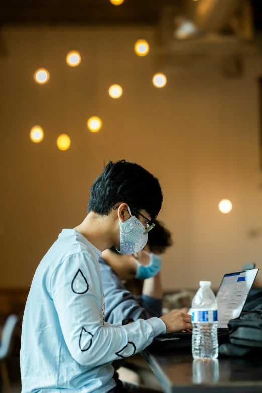 a person at a laptop with a protective face mask