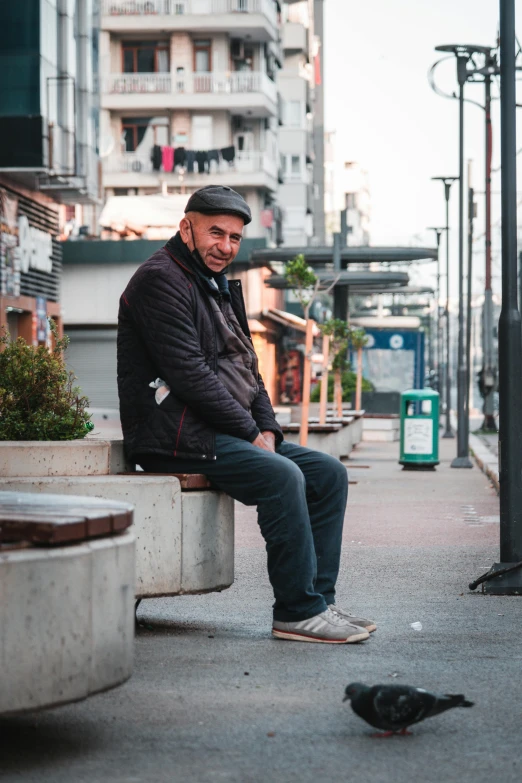 a man sitting on a cement bench with his hands clasped