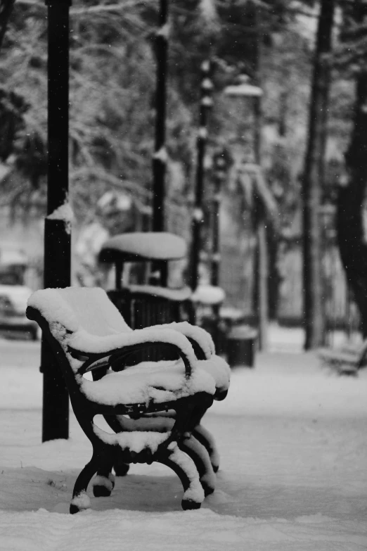 black and white po of a park bench on snowy day