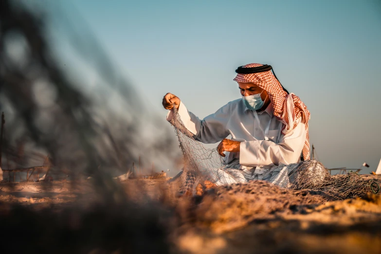 the man is sitting on a rocky hillside by the ocean