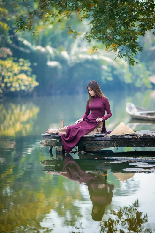 a young woman in a purple dress sitting on a dock with a dog