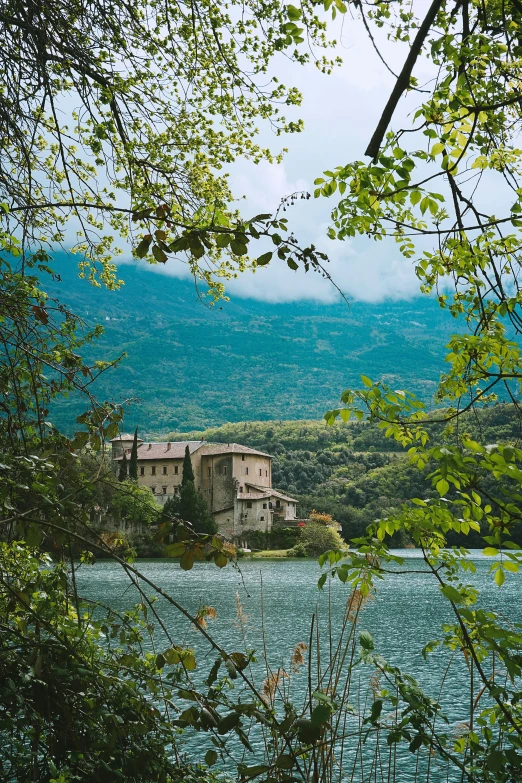 a building sitting next to the water under a cloud filled sky