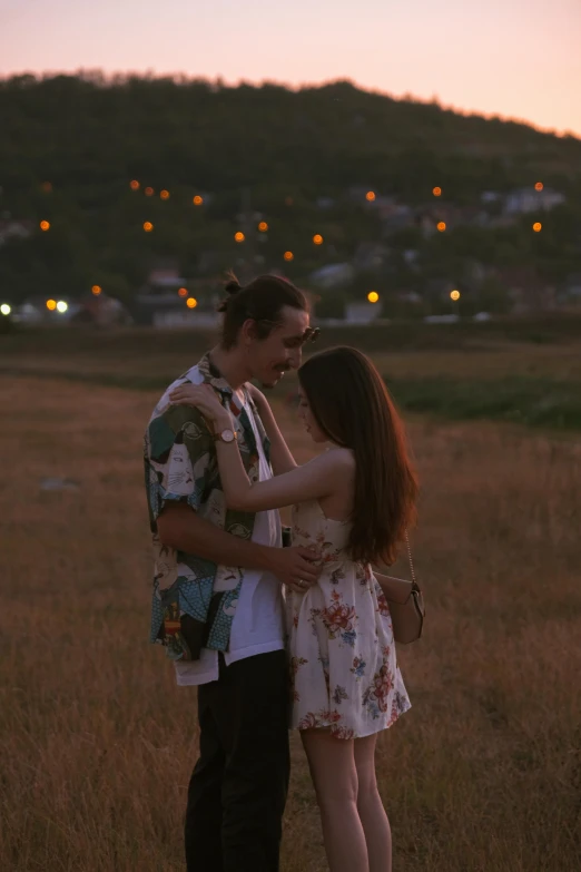 a man and a woman standing in a field with sunset