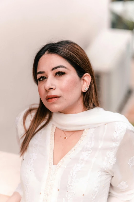 a woman in a white top and scarf, sitting