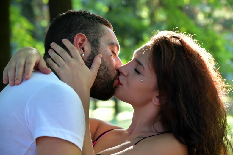 a man kissing a woman's cheek with a forest in the background