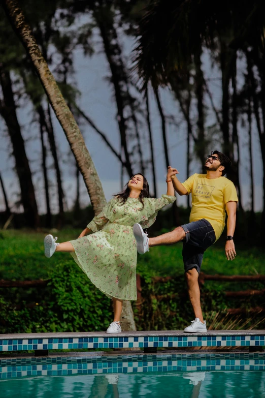 two people dancing next to a swimming pool