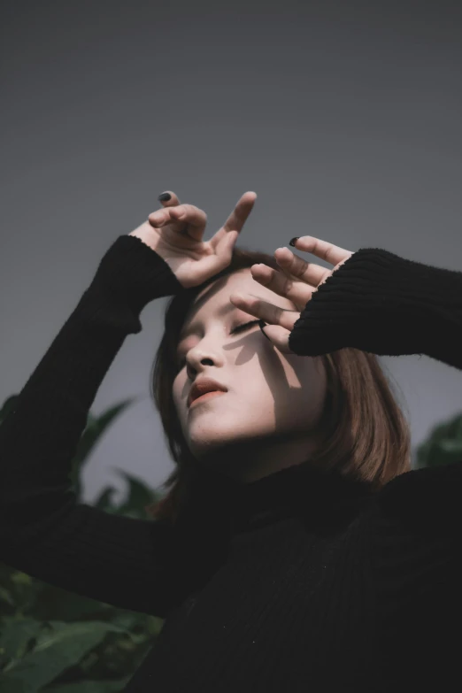 woman with finger gesture standing in front of green plants