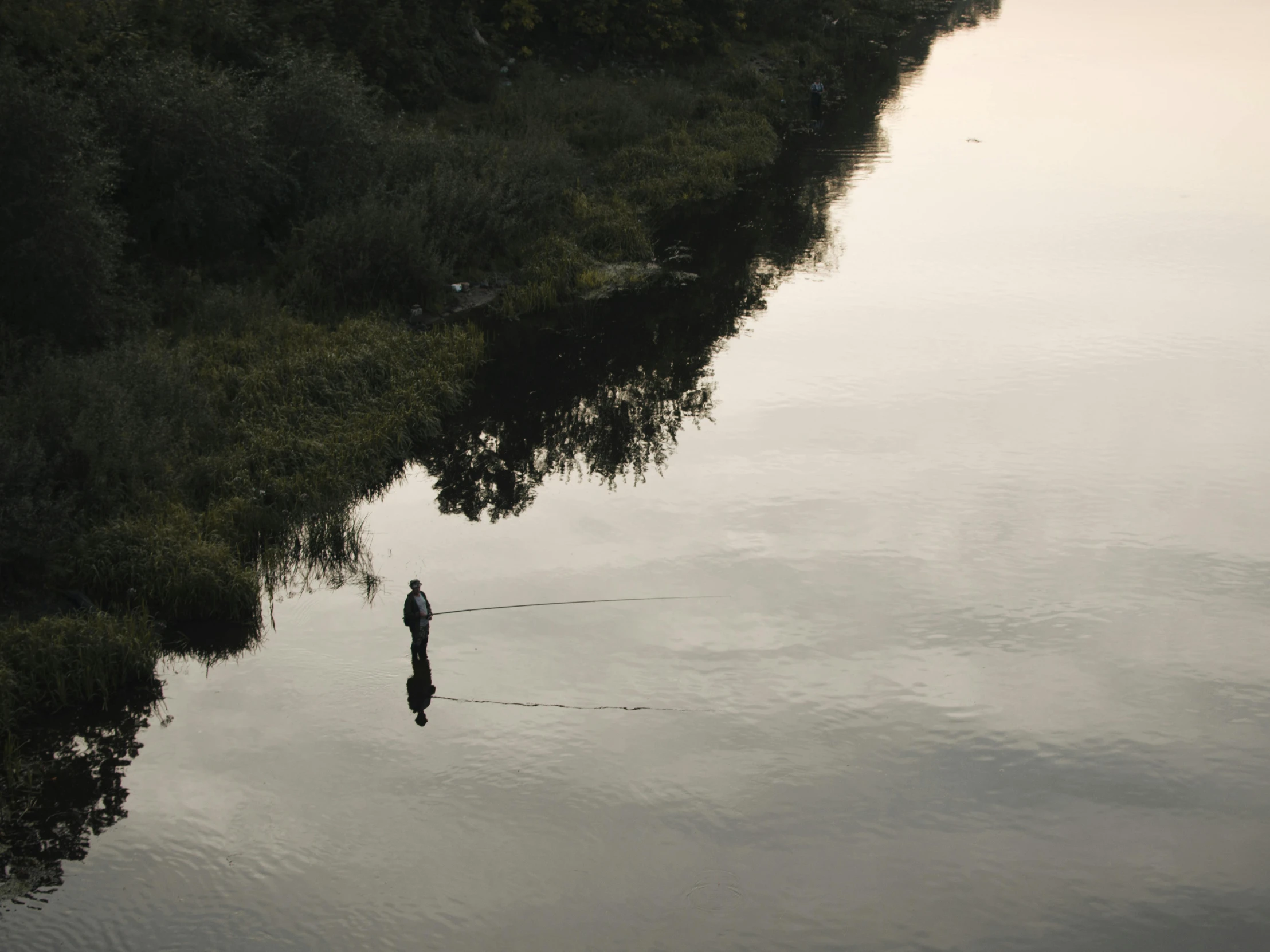 two men are fishing on the water while another man stands next to him