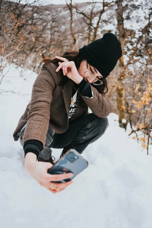 a woman kneeling in the snow taking a picture