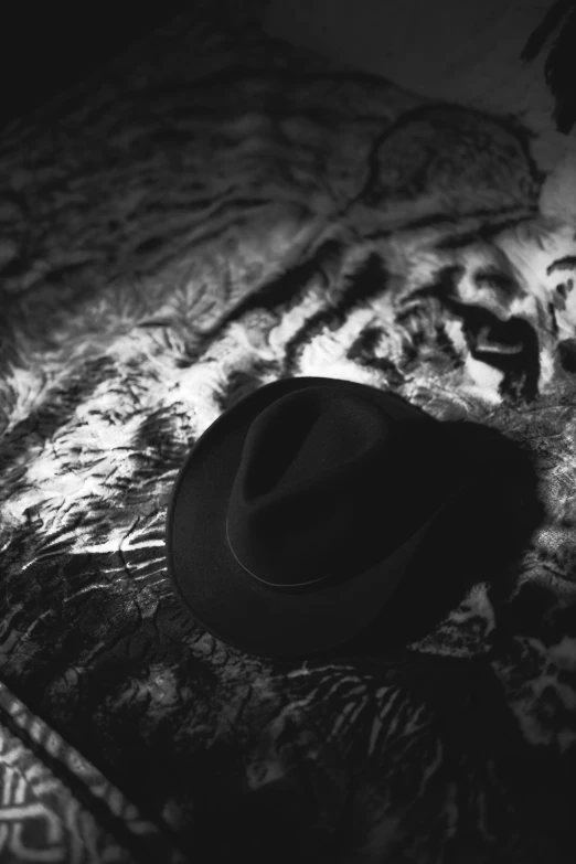 a hat laying on top of a bed with a patterned sheets