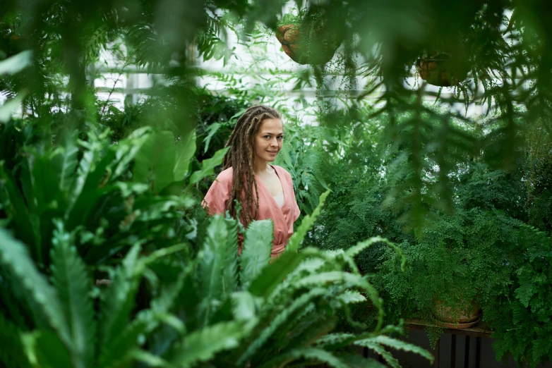 the woman is in the greenhouse with many plants