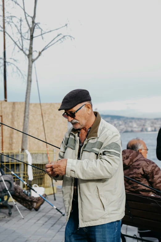 an elderly man is sitting by the water fishing