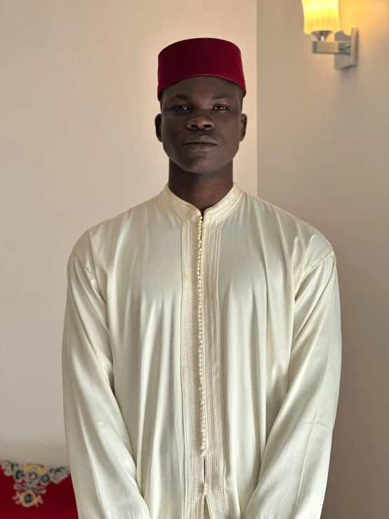 an african man standing in a living room wearing a red headdress