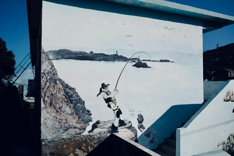 a person jumping off of a wall with a fishing pole