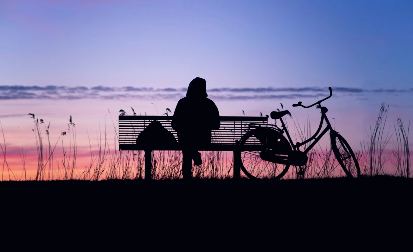 a person sitting on a bench next to a bicycle