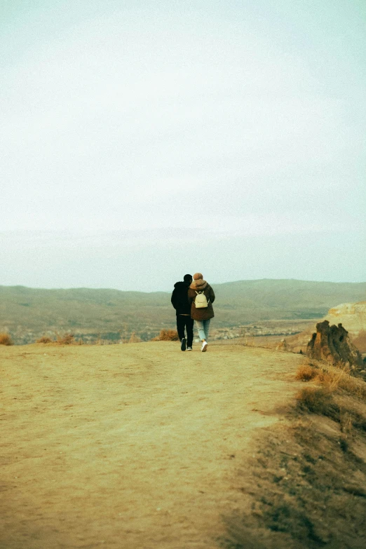 two people are walking on a road and the woman is carrying a camera