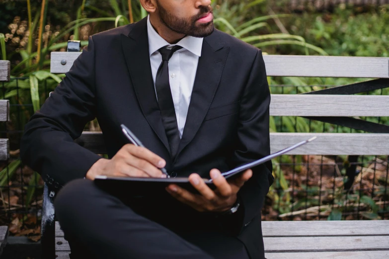 a man in a suit and tie sitting on a wooden bench