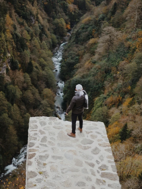 a man standing on top of a building near a creek